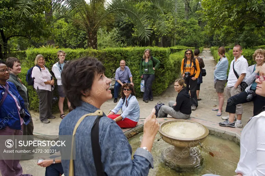Spain, Andalucia, Seville. A tour group in the garden of the Alcazar Palace.