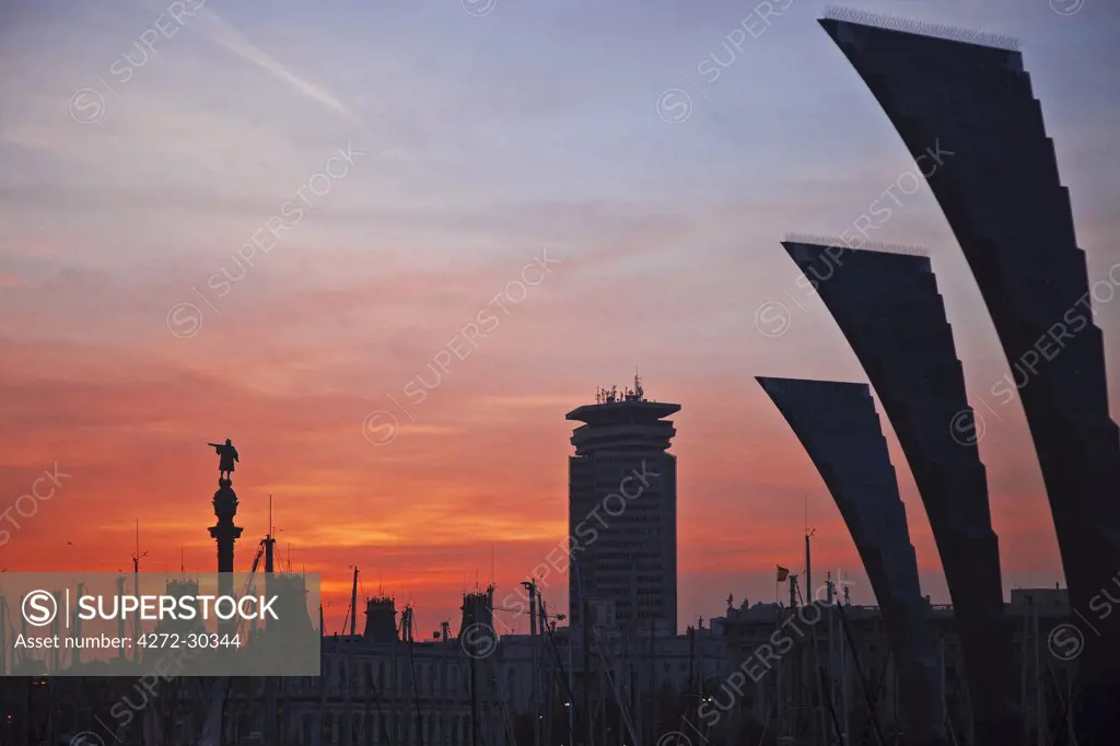 Spain, Cataluna, Barcelona, la Barceloneta, Sculpture at sunset with Barcelona Marina in and the Colom Statue in the background.