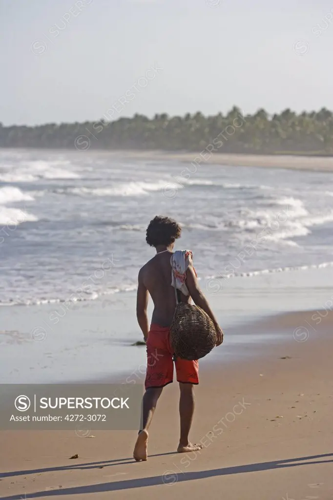 Fisherman returning home along the beach on Atlantic ocean in the Bahia region of the north east of Brazil