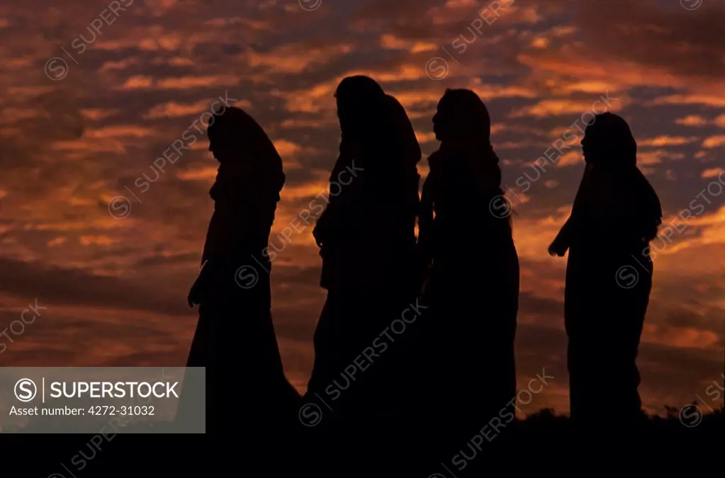 Women stroll around the fort walls at sunset.