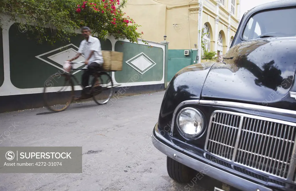 Man cycling past parked Morris Minor on Pedlar Street in Galle Fort, Galle, Sri Lanka