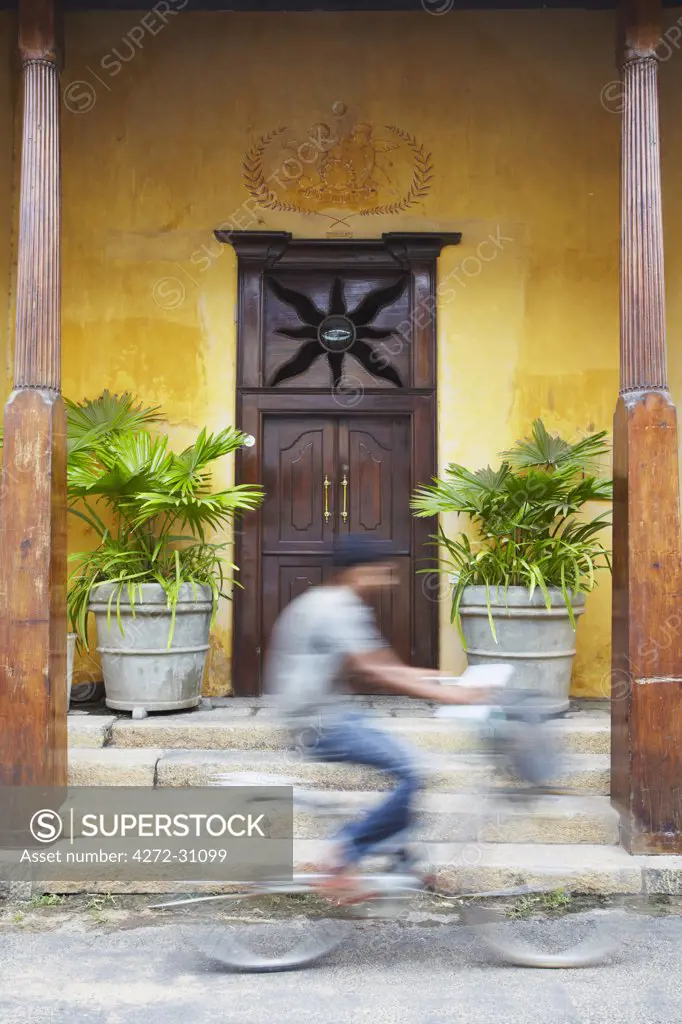 Man cycling past doorway in Old Town of Galle Fort, Galle, Sri Lanka