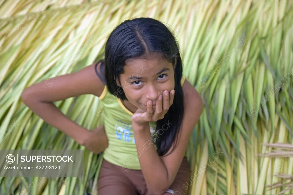 Young village girl sits on bed of newly cut crops in Jamaraqua Village watching the world go by. Jamaraqua Community, Amazon Region, Brazil