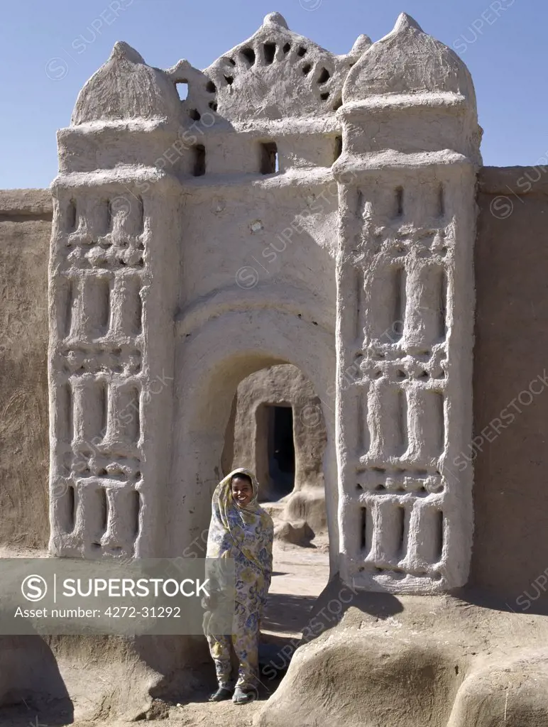 A Nubian girl stand in an archway at the village of Qubbat Selim.  Traditional Nubian architecture. Traditional Nubian architecture and plasterwork of a fine archway to a house and its courtyard at Qubbat Selim.