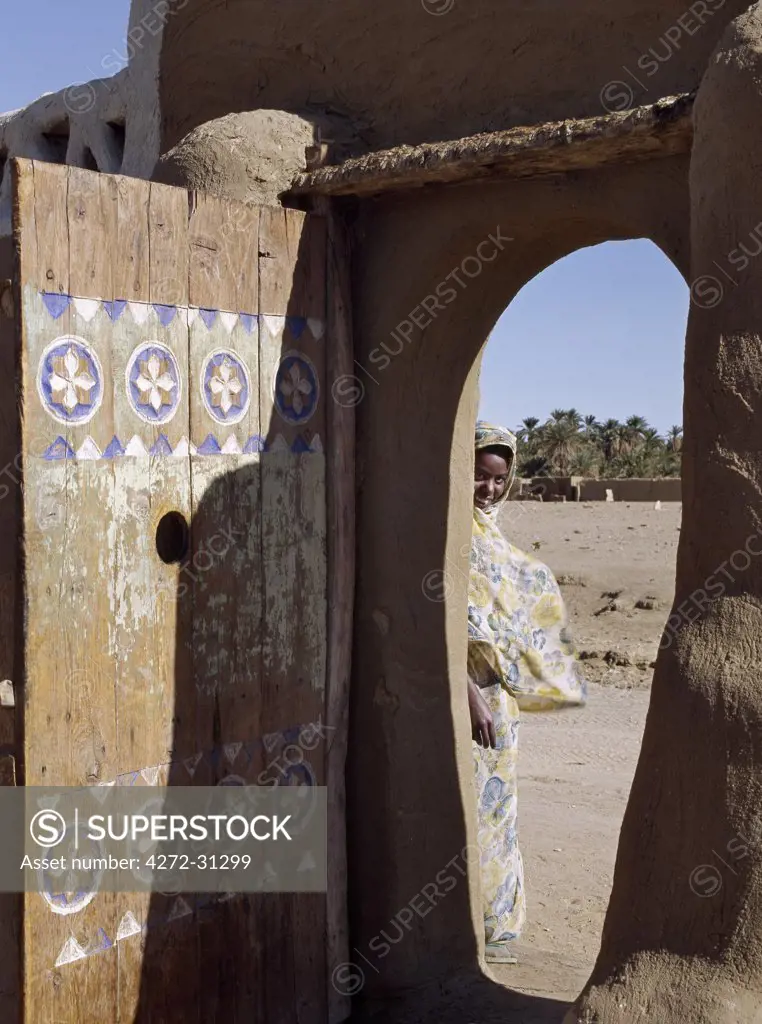 A finely carved painted door graces the arched entrance to a house compound at Qubbat Selim. This village, situated close to the River Nile in Northern Sudan, still retains much of its traditional architecture, plasterwork and decoration.