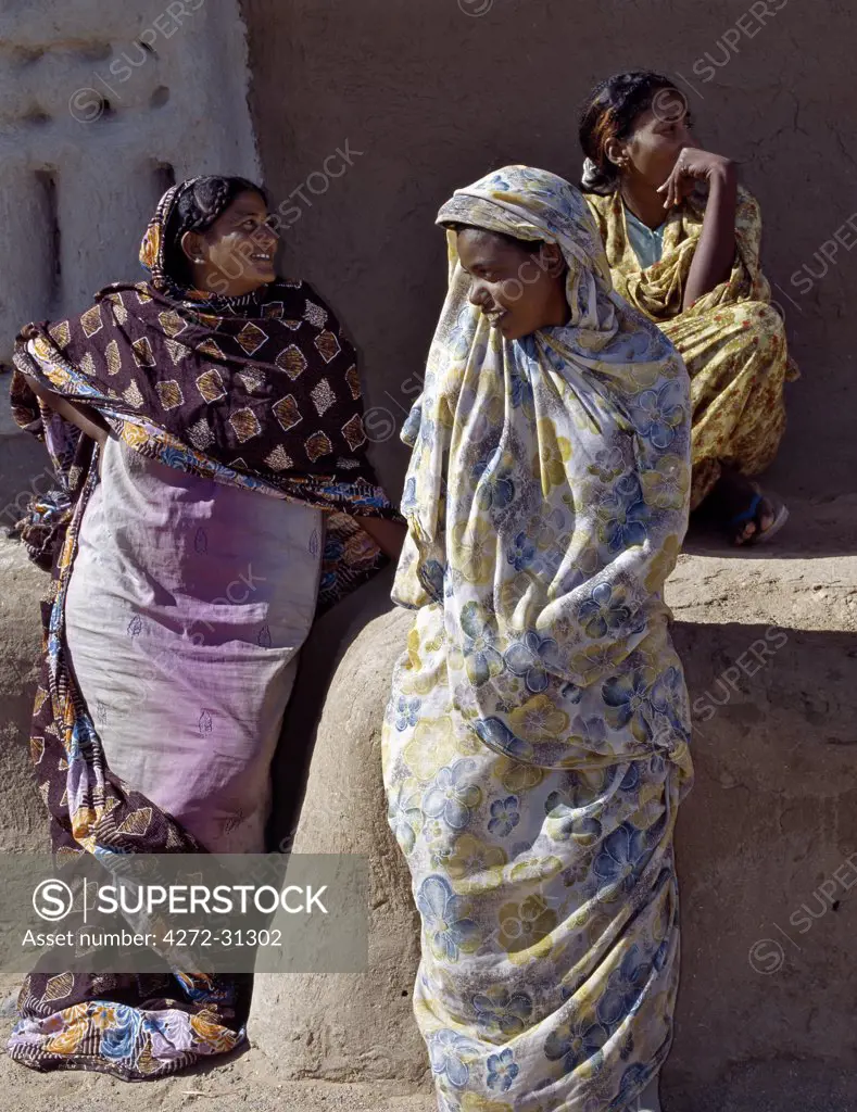 Three women relax outside a house at Qubbat Selim. This village, situated close to the River Nile in Northern Sudan, still retains much of its traditional architecture, plasterwork and decoration