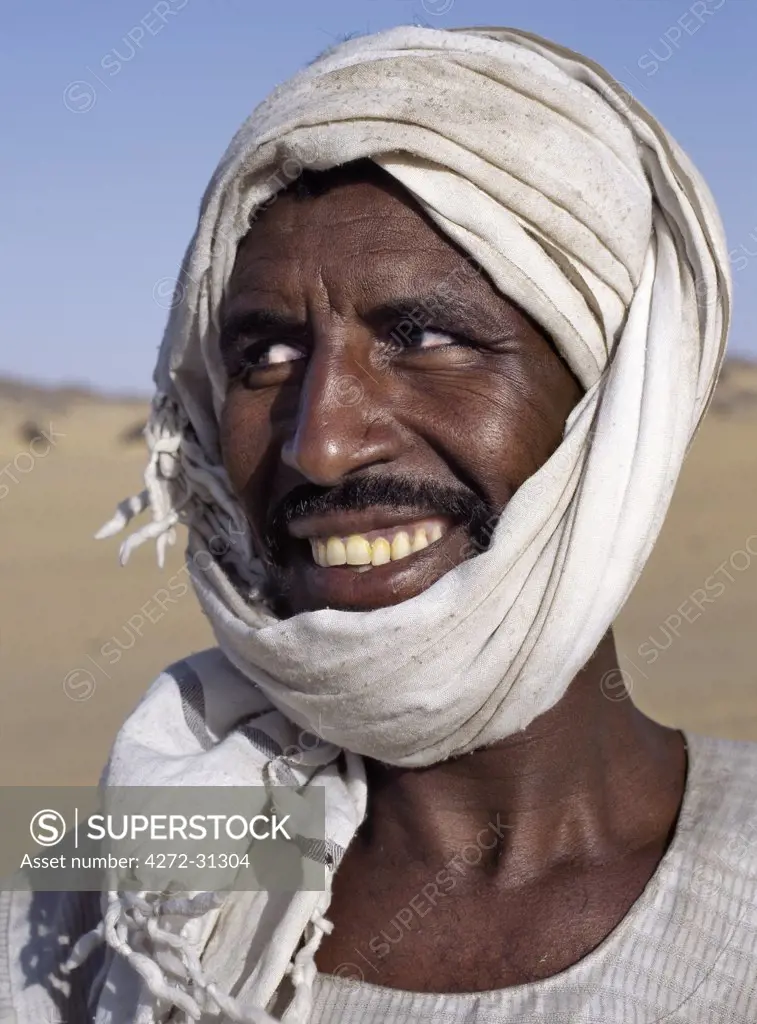 A Nubian man wearing a white turban smiles broadly at his friend.
