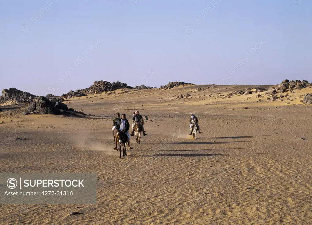 Children ride to school on donkeys along the edge of the Northern or Libyan Desert in northwest Sudan