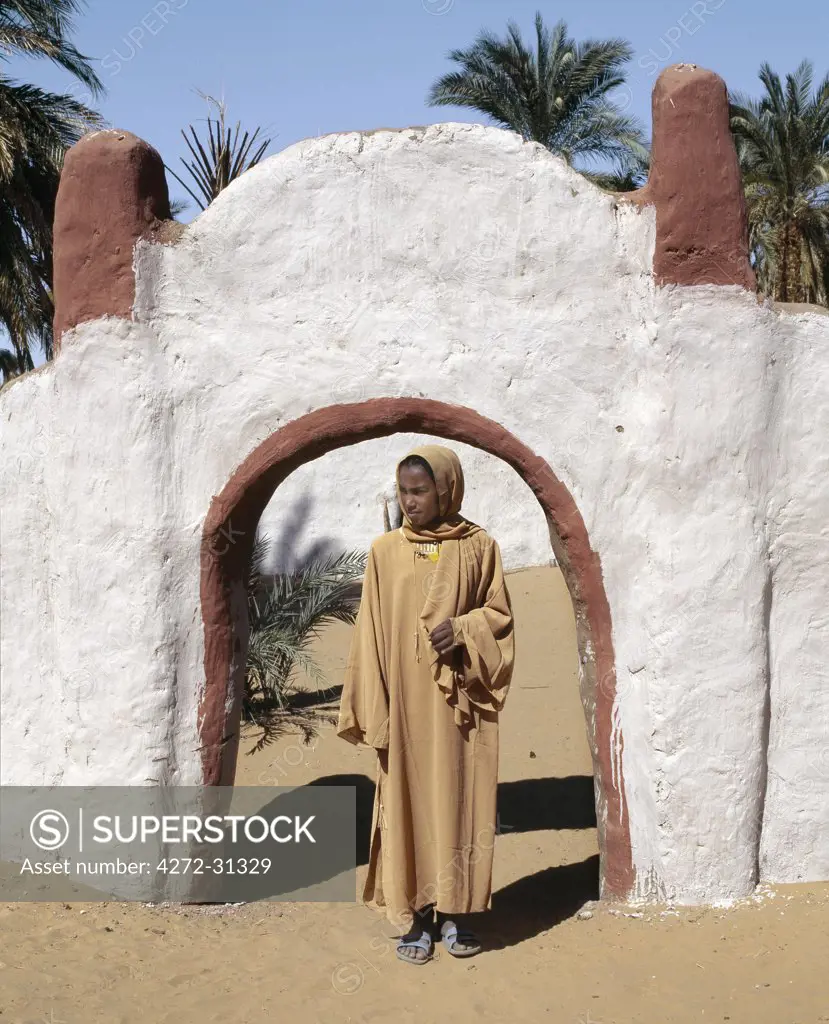 A girl stands outside the decorated archway to a house and compound at Old Dongola.