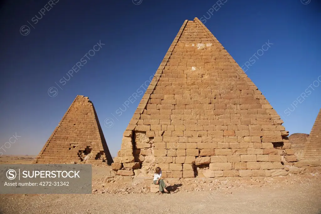 Sudan, Karima. A tourist sits at the base of an ancient pyramid at Karima.