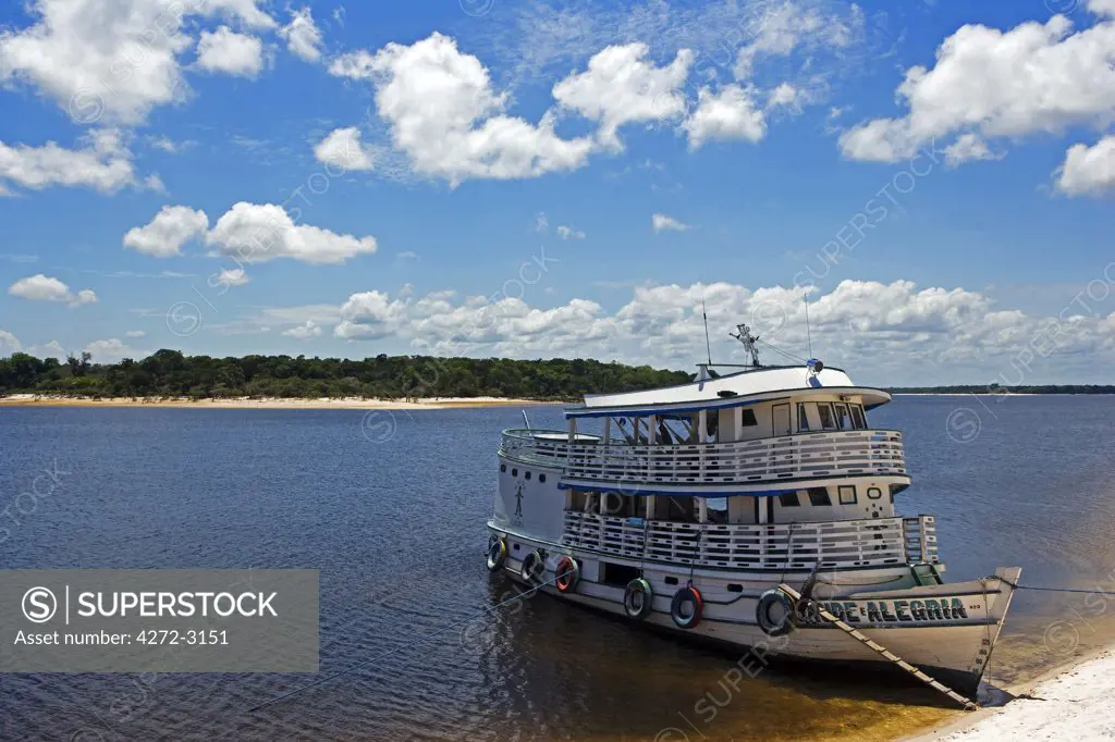 Brazil, Amazon, Rio Tapajos. A tributary of the Rio Tapajos which is itself a tributary of the Amazon has the Saude Alegria river boat secured its banks during the low waters of the dry season.