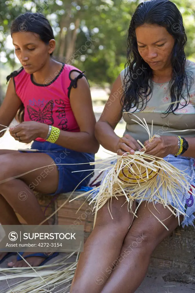 Brazil, Amazon, Rio Tapajos. A tributary of the Rio Tapajos which is itself a tributary of the Amazon. At the village of Jamaraqua, women weave traditional basketwear for sale in a co operative shop catering for Eco Tourists.
