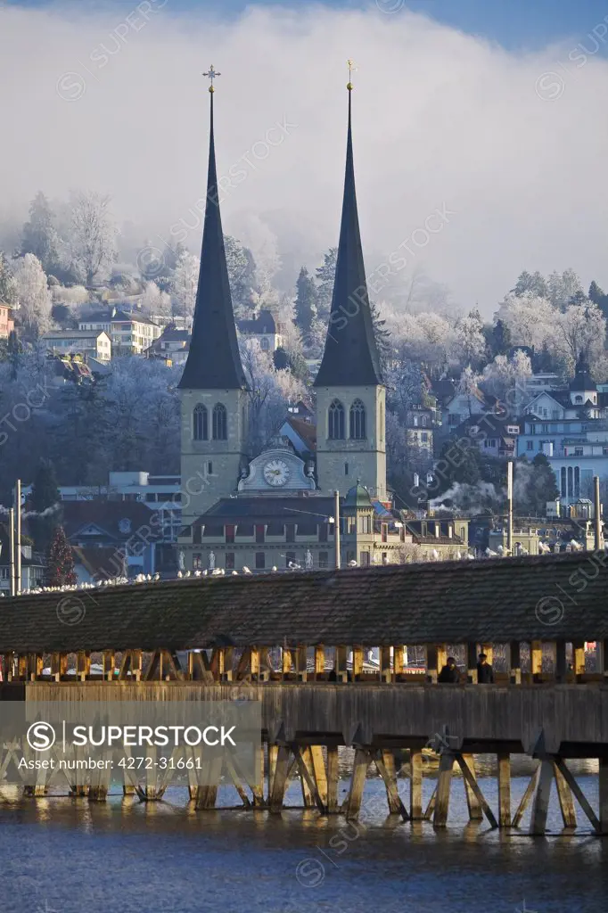 Switzerland, Lucerne, Luzern, General view of the town of Lucerne with the Reuss River and the Kappelbrucke (Chapel Bridge) in the foreground and the Hofkirche church in the background.