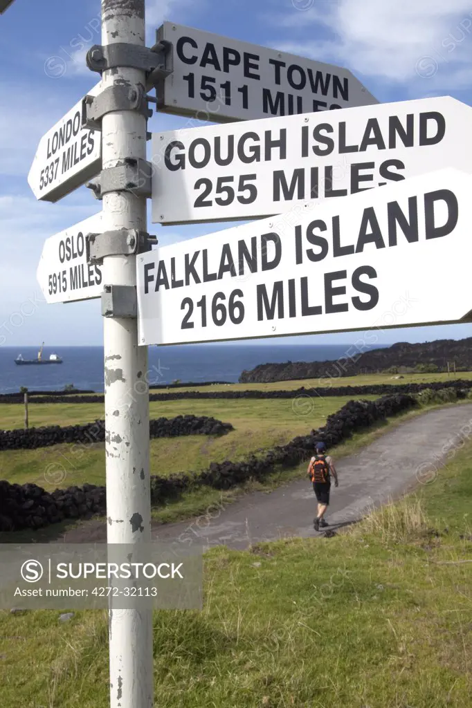 Tristan Da Cunha Island, settlement capital of Edinburgh. A hiker and a sign post indicating its nearest neighbours, the Falkland Islands. (MR)