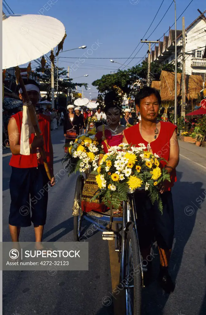 Man pushing bicycle filled with flowers at Parasol Festival, Chang Mai