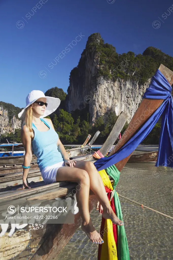 Woman sitting on long tail boat on Hat Rai Leh West beach, Railay, Krabi Province, Thailand (MR)