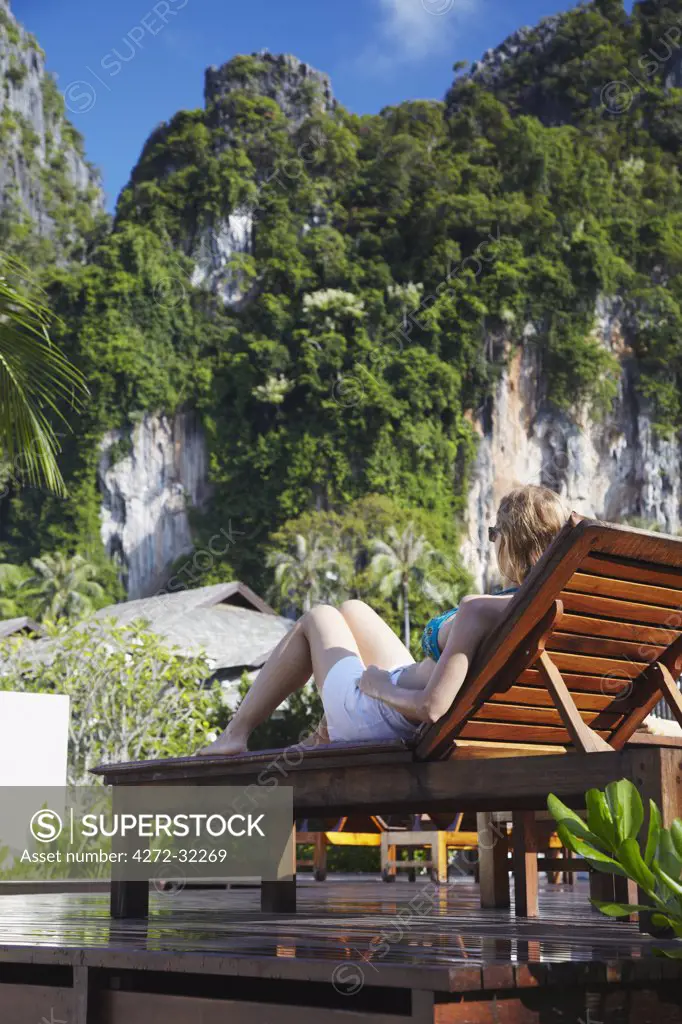 Woman sitting on sun lounger by pool in Bhu Nga Thani Resort and Spa, Railay, Krabi Province, Thailand (MR)