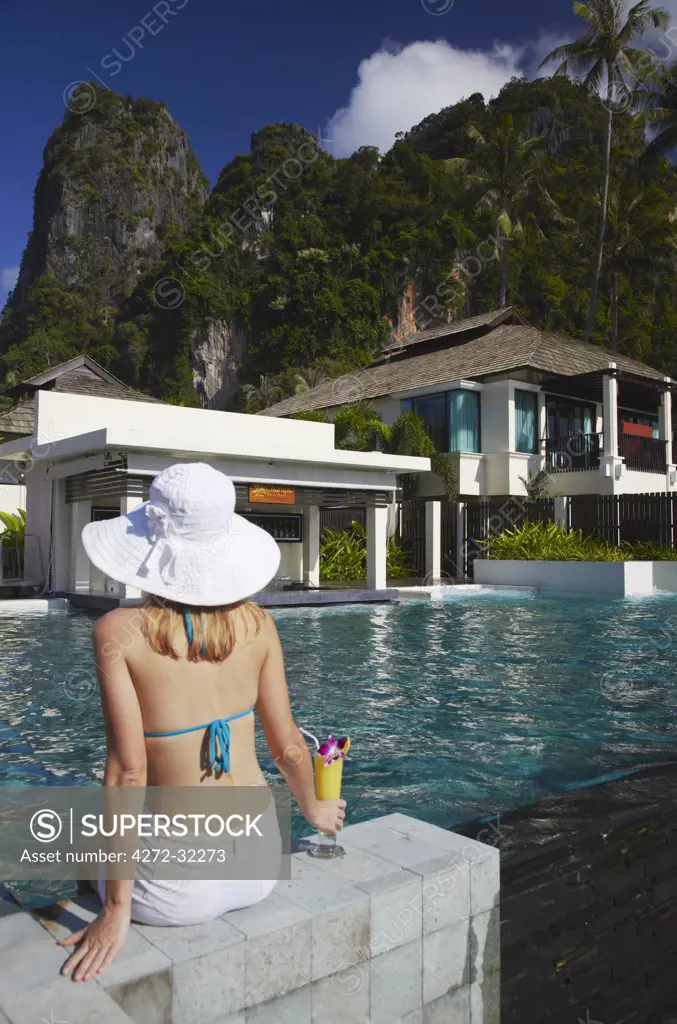 Woman relaxing by pool with drink in Bhu Nga Thani Resort and Spa, Railay, Krabi Province, Thailand (MR)