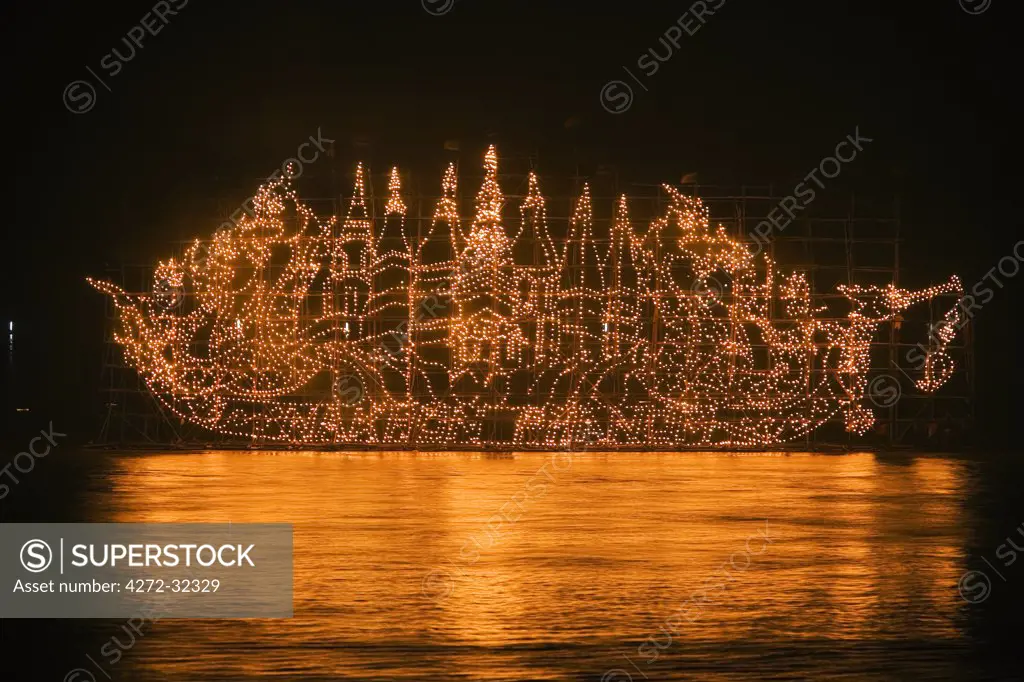Thailand, Nakhon Phanom, That Phanom.  A Fire Boat drifts on the Mekong River during the Illuminated Boat Procession.  The fire boats are giant bamboo towers decorated with lanterns in religious motifs to celebrate the end of the Buddhist Rains Retreat in October or November.