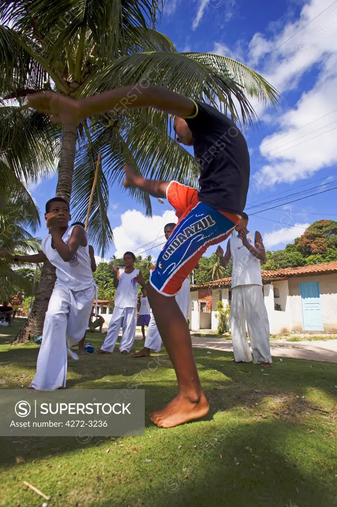 Brazil, Bahia, Boipeba Island. Young men and boys train at Capoeira the ritualistic slave dance martial dance of Brazil where staged movements hide fighting stances, defensive postures and attacking jabs