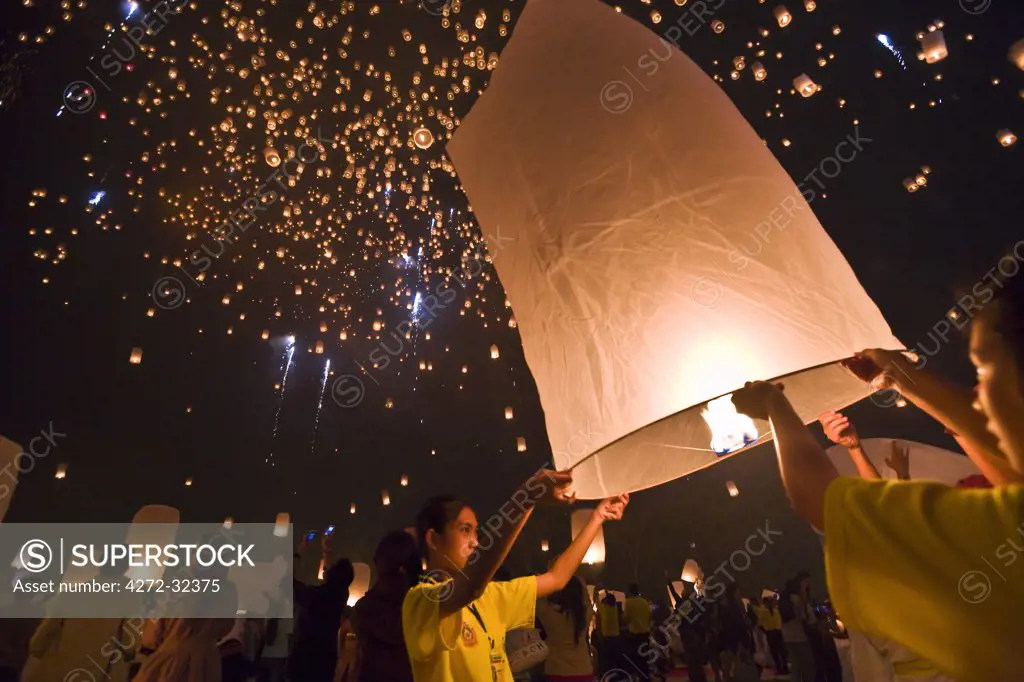 Thailand, Chiang Mai, San Sai.  Revellers launch khom loi (sky lanterns) into the night sky during the Yi Peng festival.  The ceremony is a Lanna (northern Thailand) tradition and coincides with Loy Krathong festivities.  The khom loi are released in the belief that grief and misfortune will float await them, bringing good luck.