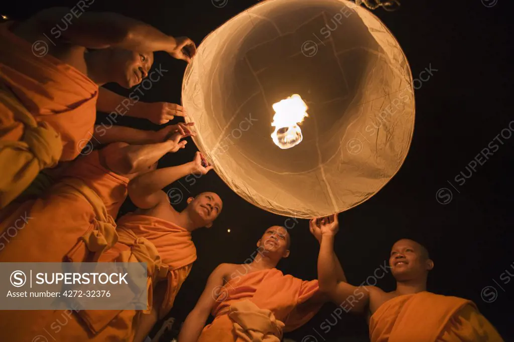 Thailand, Chiang Mai, San Sai.  Monks launch a khom loi (sky lantern) during the Yi Peng festival.  The ceremony is a Lanna (northern Thailand) tradition and coincides with Loi Krathong festivities.  The khom loi are released in the belief that grief and misfortune will float await them, bringing good luck.