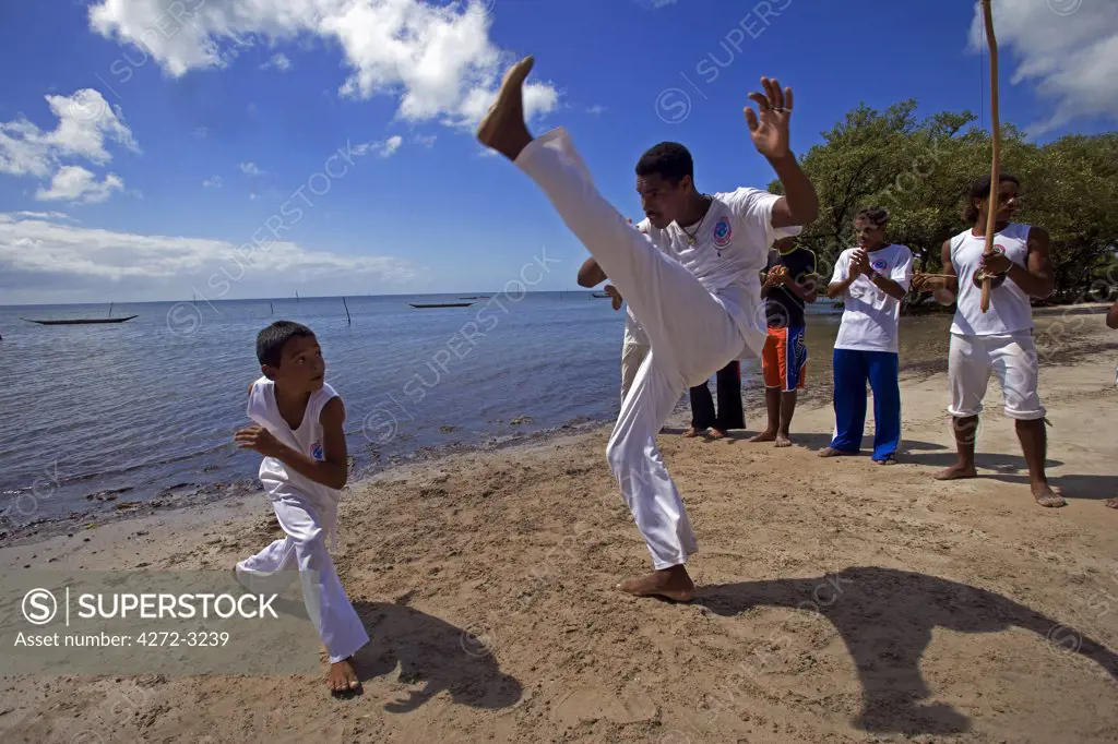 Brazil, Bahia, Boipeba Island. Young men and boys train at Capoeira the ritualistic slave dance martial dance of Brazil where staged movements hide fighting stances, defensive postures and attacking jabs.