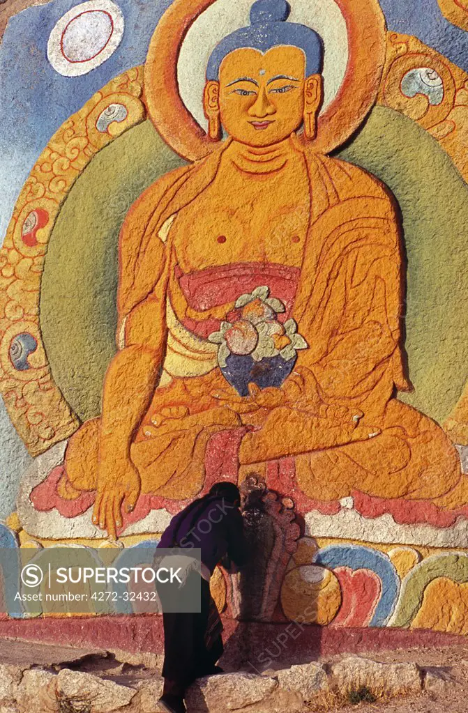 Sera Monastery.  Along Sera's kora, or pilgrimage circuit, a monk bows before a rock-painted image of Yama Dharmaraja, a bull-headed protector deity favoured by the Gelugpa school.   Behind rises a slender building from which a giant thangka, or religious painting, is unfurled during festivals.