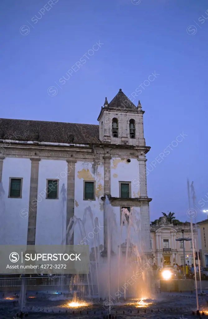 Brazil, Bahia, Salvador. The city of Salvador within the historic Old City, a UNESCO World Heritage site, the side view of the Jesuit Cathedral of Salvador at night with flood lit fountains in the foreground.