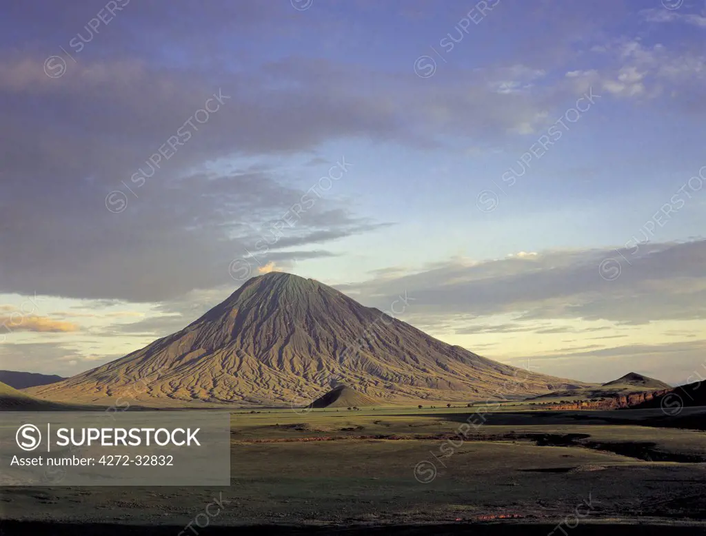 Ol doinyo Lengai, the Maasais Mountain of God, bathed in early morning sun.  It is the only active volcano in the Gregory Rift  - an important section of the eastern branch of Africas Great Rift Valley. This 9,400 foot high volcano with deeply eroded sides stands 7,000 feet above the surrounding plains.