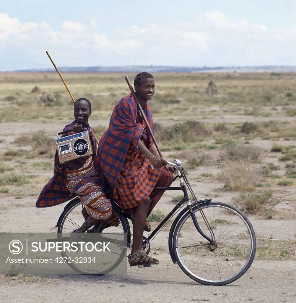 Old and new.  Dressed traditionally and carrying familiar wooden staff, two young men give hints that the lifestyle of younger Maasai generations is changing gradually in Tanzania.