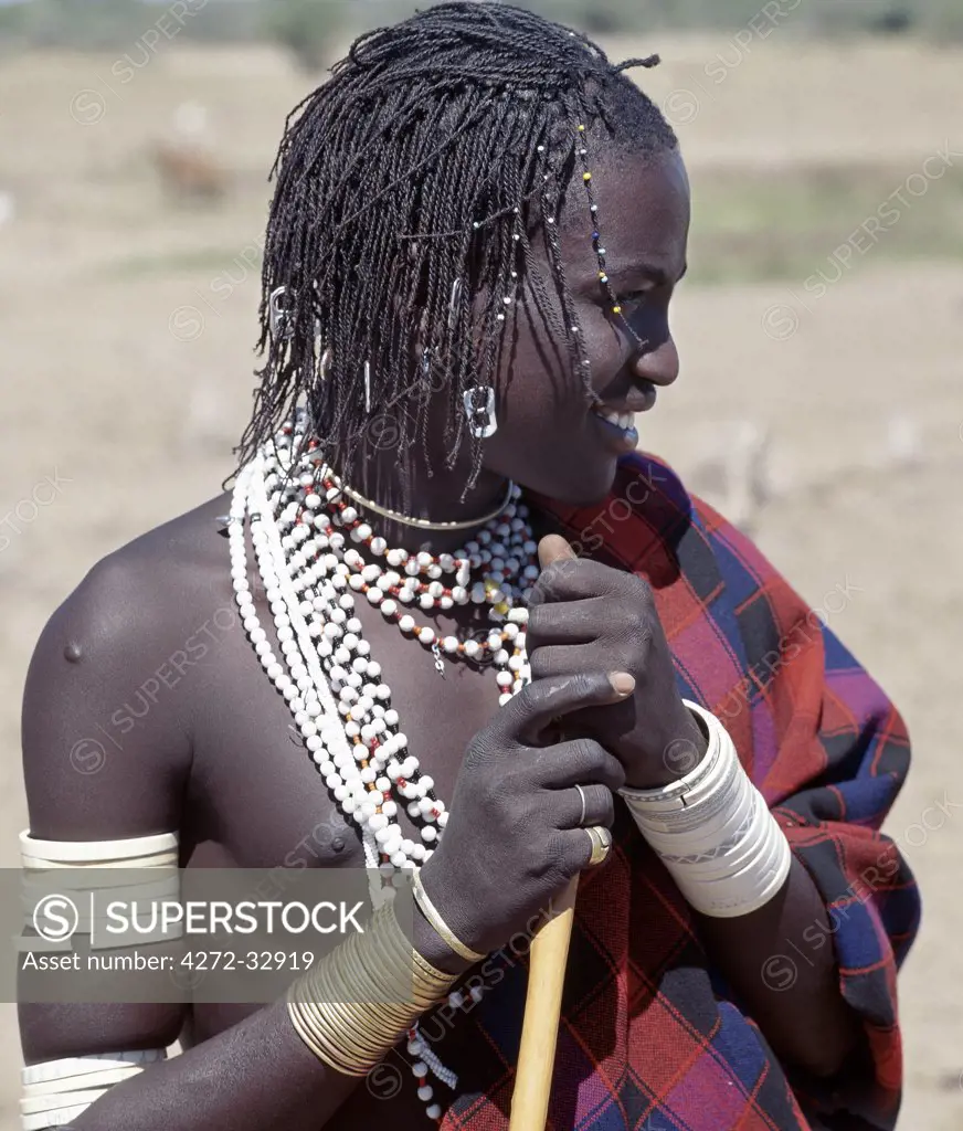 A Datoga young man in traditional attire. His braids are embellished with beads and aluminium can openers. Many of his white plastic bracelets are beautifully decorated with abstract and geometrical designs, long ago these bracelets would have been made of ivory.