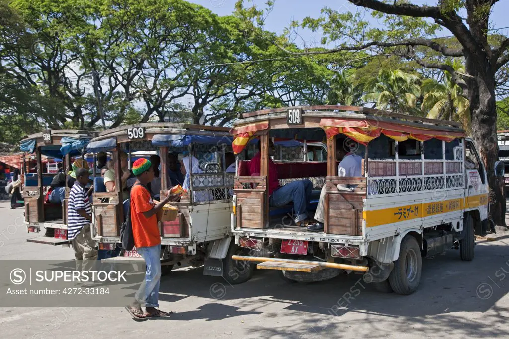 Tanzania, Zanzibar, Stone Town. Colourful country buses, known as Daladala, line up outside the municipal market to await passengers. This form of transport is reliable, inexpensive and popular.