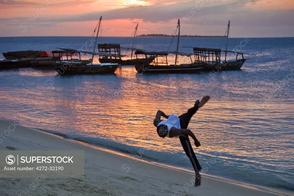 Tanzania, Zanzibar. At sunset, an acrobat practices somersaulting on the sandy beach west of Stone Town.