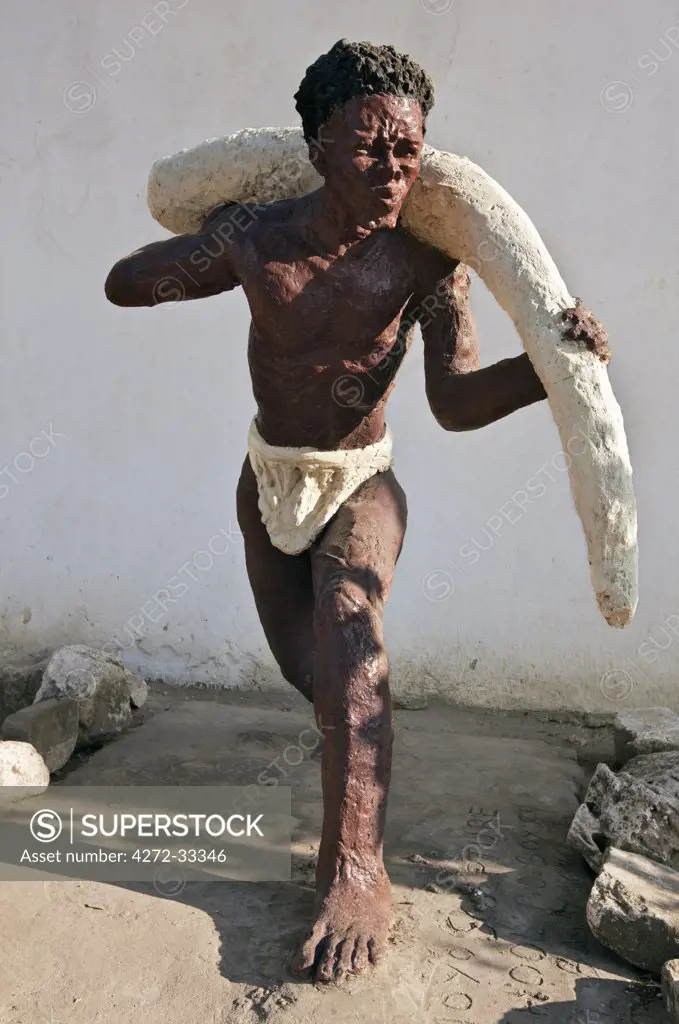 The modern sculpture of a slave carrying ivory outside the 19th century Caravan-serai building at Bagamoyo.  Bagamoyo was a major centre for exporting slaves in the 19th century.