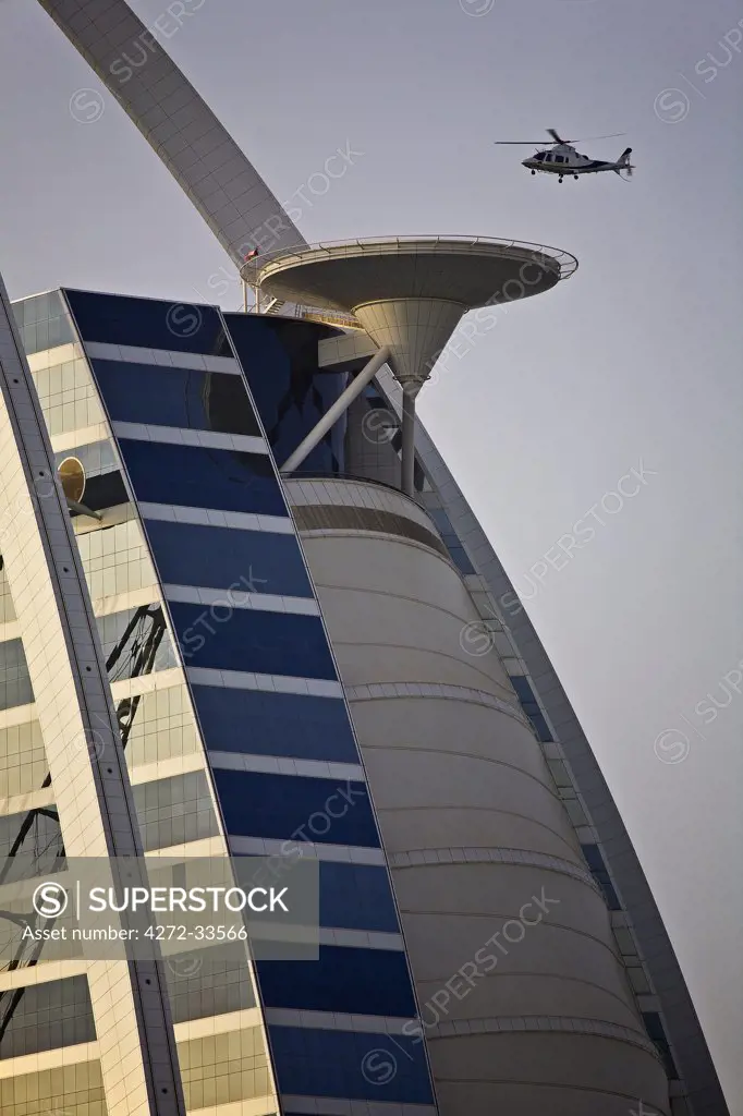 United Arab Emirates, Dubai, Um Suqaim Second District; a helicopter approaches the helicopter landing pad of the 7 Star luxury Burj Al Arab Hotel.