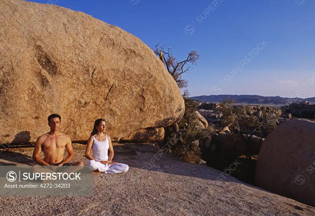 Yoga in the Joshua Tree National Park. The male is meditating in the 'Sukhasasana', easy pose. He is practicing 'bahya kumbhaka' which is holding his breath after exhalation. The female is meditating in the 'Padmasana' half lotus pose. This is one of the most useful and important poses, it is used for meditation and the Buddha is often depicted in it.