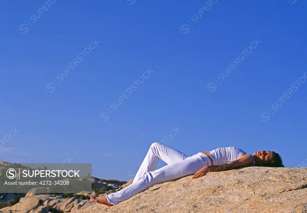 Yoga in the Joshua Tree National Park. The female in this shot is holding the 'Savasana' corpse pose, entering a state of profound relaxation.