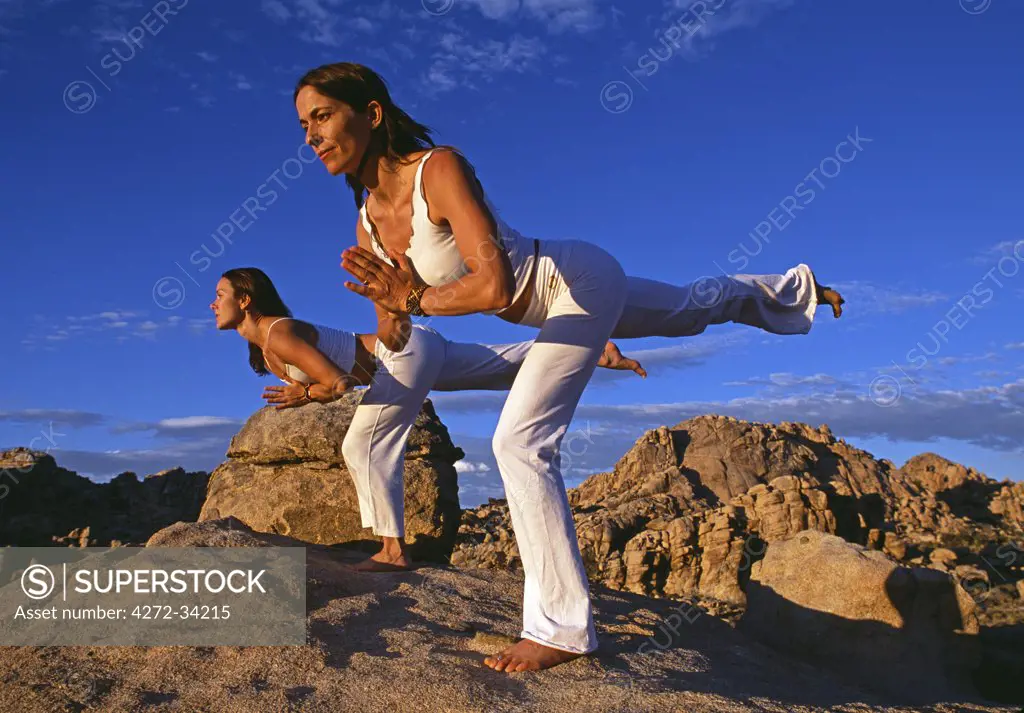 Yoga in the Joshua Tree National Park, both women in 'Virabhadrasana 3' warrior 3