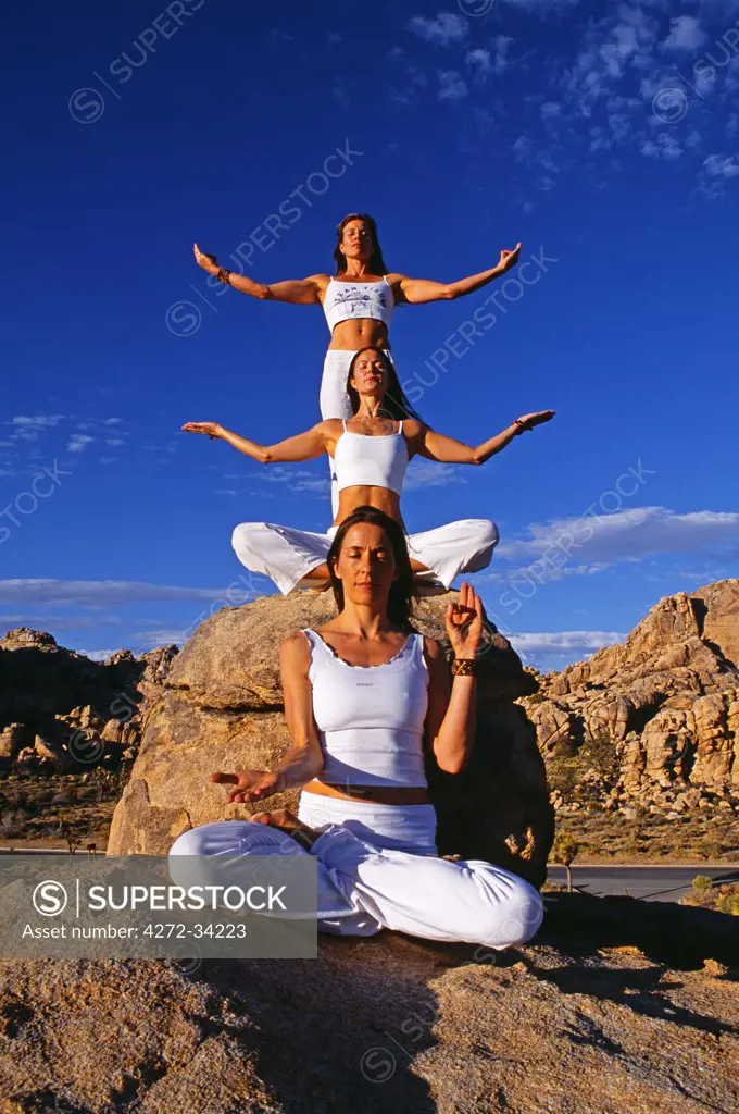 Yoga in the Joshua Tree National Park, all three are in different poses, 'Padmasana' Lotus pose, 'Sukhasasana' easy pose and a variation of 'Tadasana' standing pose with arms out to the side.