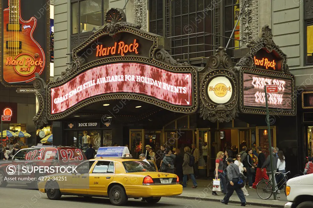 A yellow New York City cab passes in front of the Hard Rock Cafe in Times Square