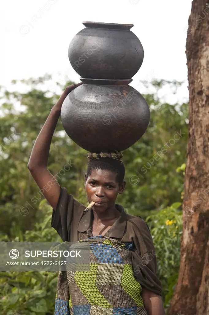 Burundi. A woman uses traditional pots to transport her goods to market.