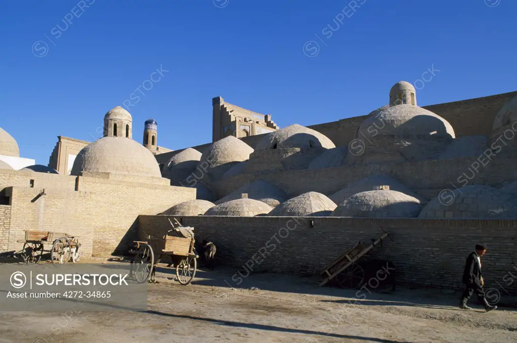 An Uzbek man walks beside the many domed walls of the Ichan Kala, the old city of Khiva.