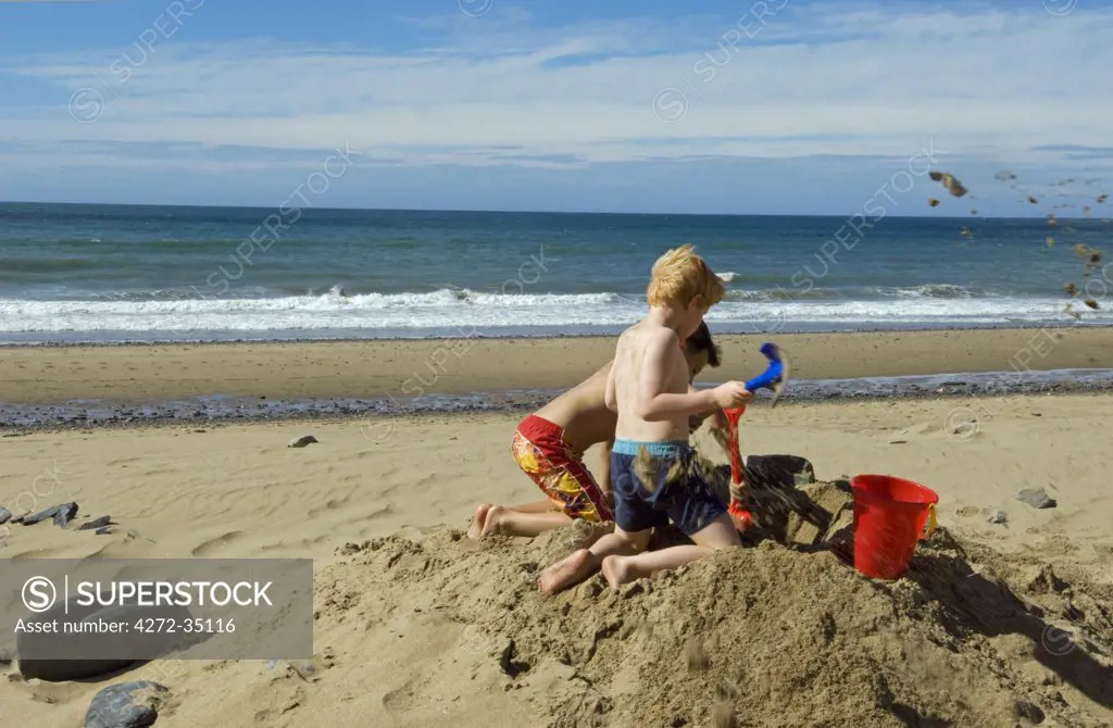 UK, Wales, Ceredigion. Two young boys build a sandcastle on Penbryn Beach in Cardiganshire.