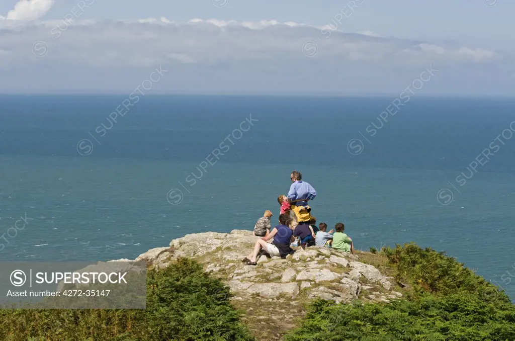 UK, Wales, Pembrokeshire. A family look out over Fishguard Bay and the Irish Sea from the Pembrokeshire Coastal Path on Dinas Head.