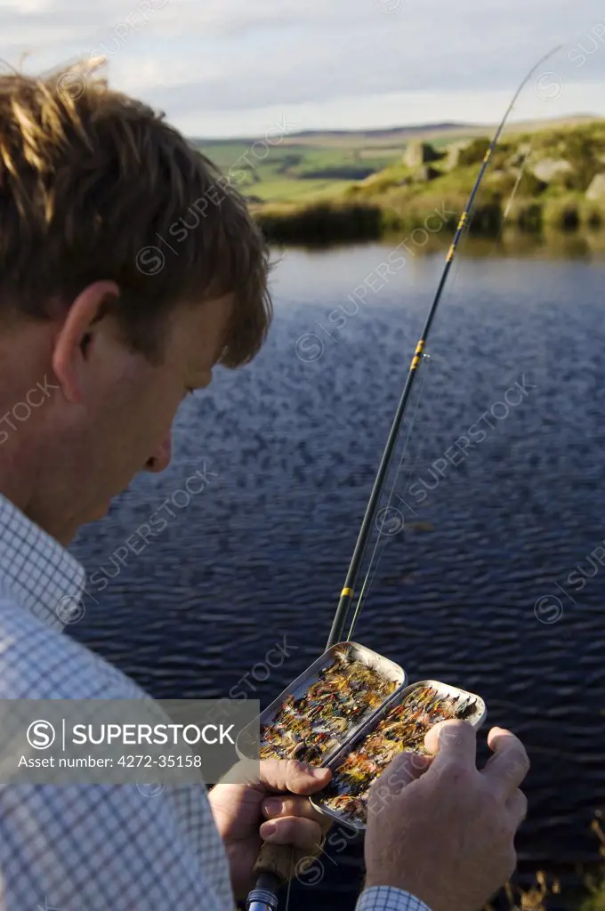 UK, Wales, Conwy. A fisherman selects a fly from his fly-box whilst trout fishing in North Wales (MR)