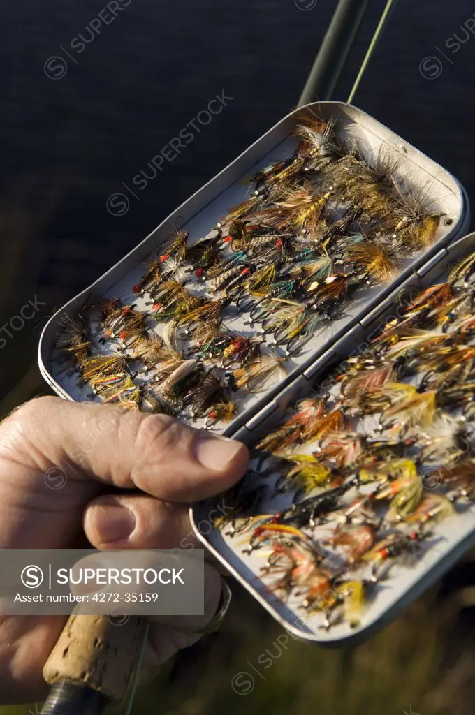 UK, Wales, Conwy. A fisherman selects a fly from his fly-box whilst trout fishing in North Wales (MR)