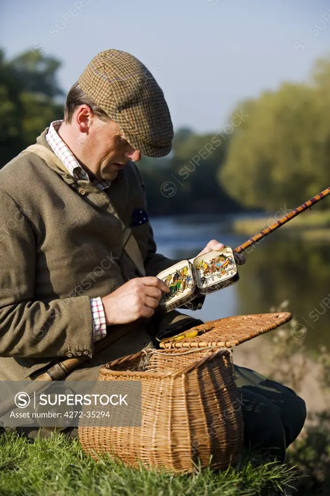 Wales, Wrexham. A fisherman selects a fly while salmon fishing on the River Dee
