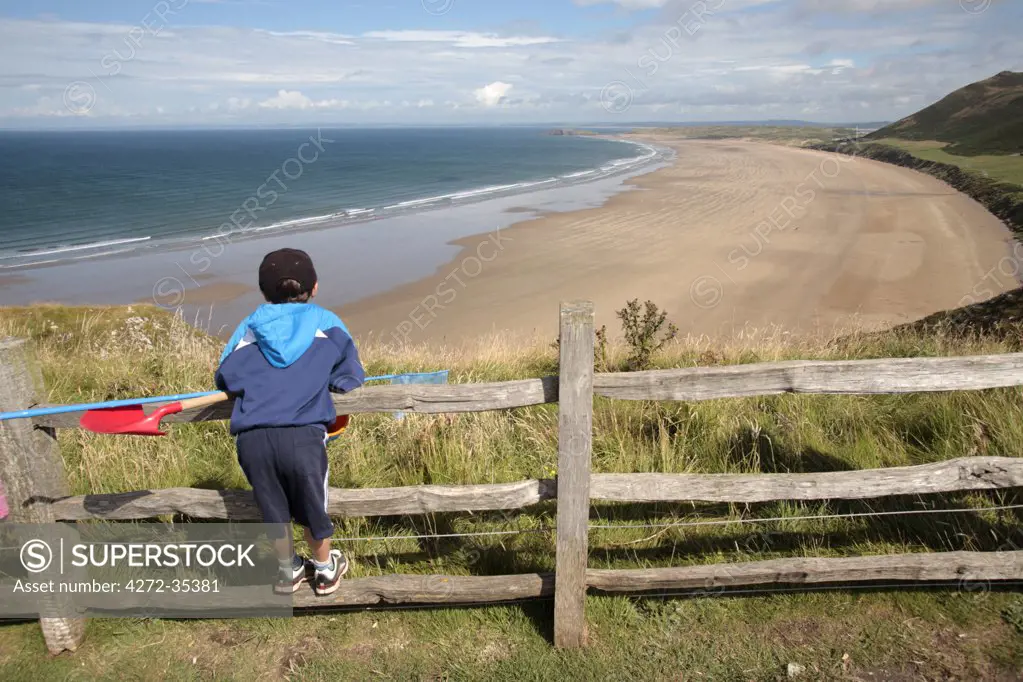 Wales; Gower Peninsula. A young boy looks out across Rhossili Bay. (MR)