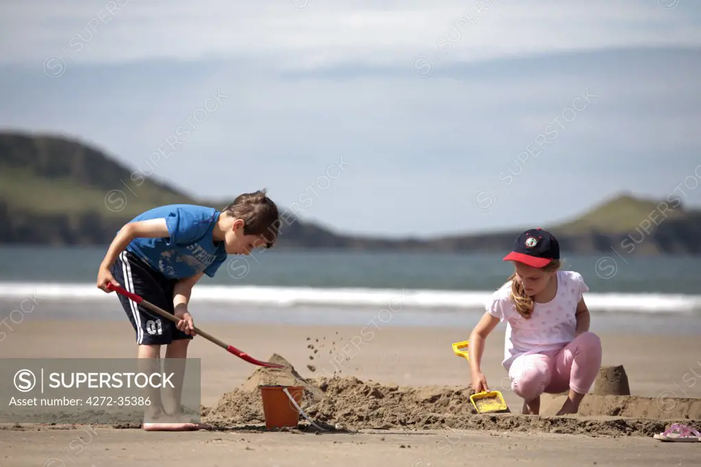 Wales, Gower. Children building sandcastles on the beach at Rhossili during low tide. (MR)